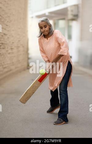Une vieille femme jouant au cricket. Banque D'Images
