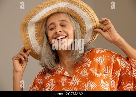 Une vieille femme heureuse qui lui fait étalage de son chapeau. Banque D'Images