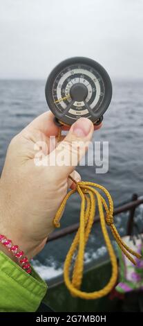 Homme mesurant la vitesse du vent en mer avec un anémomètre de poche Vintage. Banque D'Images