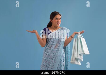 Une jeune femme debout avec des sacs de transport dans sa main. Banque D'Images