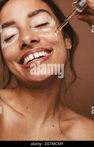 Gros plan de la femme souriante prenant soin de l'état de la peau. Dermatologue appliquant la médecine liquide pour traiter le vitiligo. Banque D'Images
