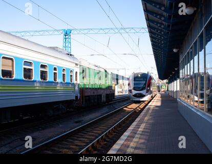 Le train à grande vitesse moderne se déplace rapidement le long de la plate-forme. Arrivée du train. Le train arrive à la gare. Vieux trains de voyageurs debout. Banque D'Images