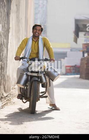UN HOMME DE TRAITE RURAL QUI SE POSE VOLONTIERS EN CHEMIN POUR LIVRER DU LAIT Banque D'Images
