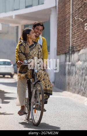 UN COUPLE RURAL SE REGARDANT LES UNS LES AUTRES TOUT EN FAISANT UN VÉLO Banque D'Images