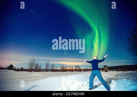 Homme touriste regarde aurora nord lumières nuit à la forêt, foyer doux. Banque D'Images