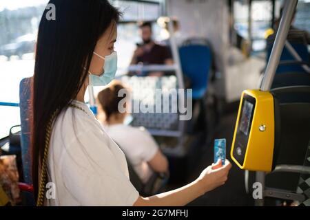 Femme asiatique payant sans concession avec une carte en plastique pour les transports en commun en bus, tram ou métro Banque D'Images