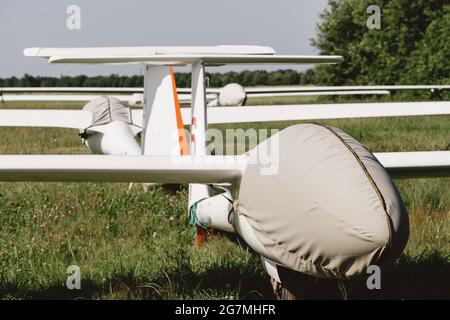 Avion sans moteur à voilure fixe du planeur couvert sur le parking de l'aérodrome, piste d'aviation de club en pleine ascension Banque D'Images