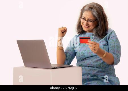 UNE FEMME ADULTE HEUREUSE EXPRIMANT LA JOIE DE TERMINER LA TRANSACTION EN LIGNE Banque D'Images