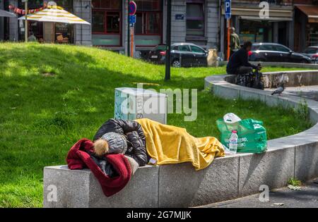 Femme sans abri dormant sur le mur du jardin du centre-ville - Saint Gilles, Bruxelles, Belgique. Banque D'Images