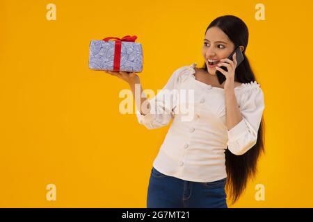 Une femme avec un cadeau dans sa main parlant au téléphone. Banque D'Images