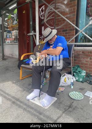 Un résident local prend un peu de sommeil sur le trottoir à l'extérieur de son bâtiment sur Manhattan Avenue dans le quartier Greenpoint de Brooklyn, New York. Banque D'Images