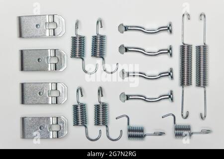 Kit de réparation pour freins, plusieurs ressorts métalliques, axes, limiteurs - colliers. Jeu de pièces de rechange pour la réparation des freins de voiture. Détails sur fond blanc, espace de copie disponible. 4K UHD. Banque D'Images