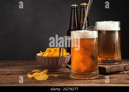 Verser de la bière fraîche dans des tasses de bière sur un fond brun foncé. Banque D'Images