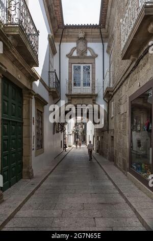 Guimarães / Portugal - 12 09 2020 : vue sur une rue ancienne et étroite avec des bâtiments classiques dans le centre ville de Guimarães, couple marchant sur fond Banque D'Images