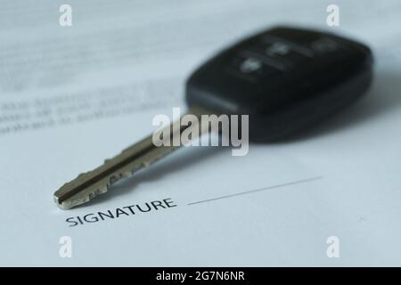 Il y a un contrat et des clés de voiture sur la table, l'accent est mis sur les clés et les signatures. Image floue. Banque D'Images