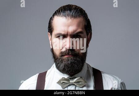 Portrait de beau barbu homme en chemise blanche et noeud papillon, bretelles. Gros plan d'un homme son noeud papillon. Homme de barbe en noeud papillon et bretelles. Homme Banque D'Images