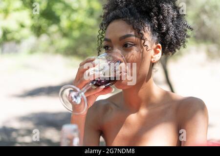 Descente africaine jeune femme boit du vin rouge à la campagne Banque D'Images