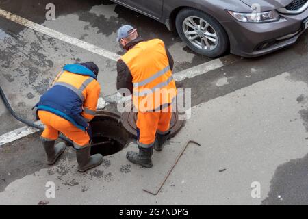 Travailleurs sur la trappe d'égout ouverte d'une rue Banque D'Images