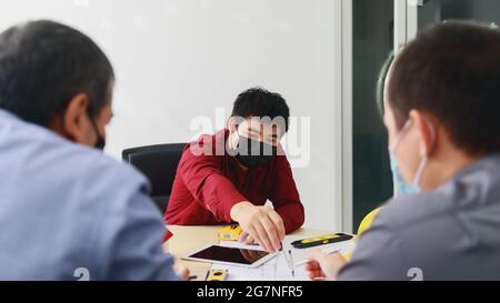 Une équipe d'architectes et d'ingénieurs qui portent des masques de protection travaillent ensemble dans un bureau. Concept architectural. Pratique de distance sociale preven Banque D'Images