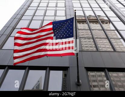 Drapeau américain agitant devant un gratte-ciel à New York. Banque D'Images