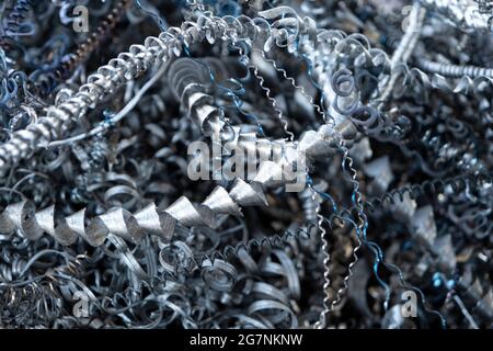 Recyclage des déchets d'acier. Aluminium, déchets de copeaux de fer après l'usinage de pièces métalliques sur un tour cnc. Gros plan de copeaux d'acier torsadés abstraits en spirale. Banque D'Images