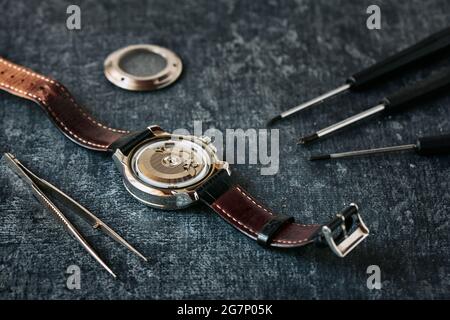 Montre-bracelet ouverte, brucelles et tournevis, concept de réparation de montre, gros plan, faible profondeur de champ Banque D'Images