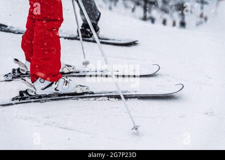 Gros plan des jambes de skieur en bottes et en skis. Piste de ski, mise au point sélective floue. Loisirs d'hiver, style de vie sportif et activités de plein air Banque D'Images
