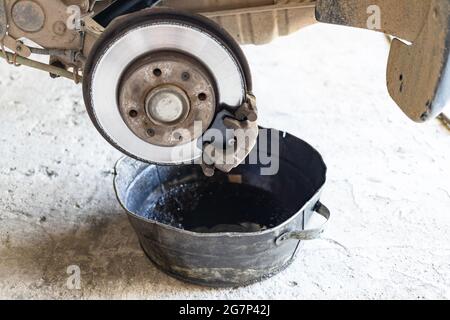 l'ancien liquide de frein est vidangé dans un bassin d'acier dans un atelier de voitures rurales (accent sur le nouveau segment de frein) Banque D'Images