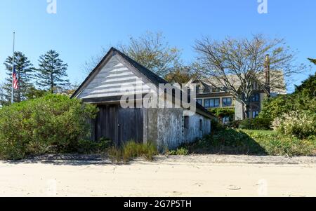 Une maison de bateau sur la côte avec du sable en face, et une maison de domaine en arrière-plan. Banque D'Images