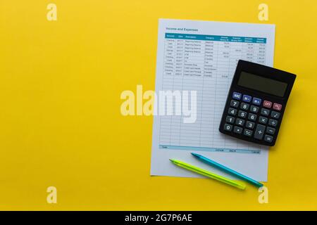 Vue de dessus de la calculatrice, feuille de calcul avec revenus et dépenses et stylos sur une surface jaune Banque D'Images