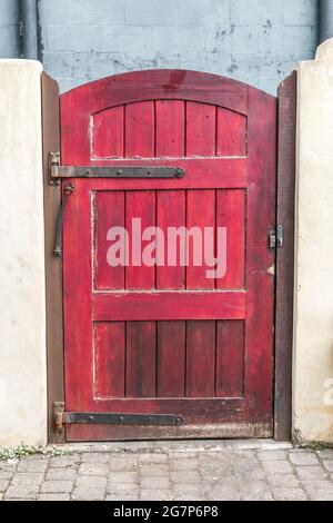 Rustique et peint en rouge avec des intempéries extérieur jardin cour porte d'une maison dans la ville pour une entrée de trottoir Banque D'Images