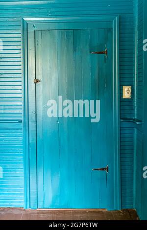 Porte de placard intérieure turquoise avec murs peints de la même couleur et garniture dans la vieille maison avec un tableau original authentique. Banque D'Images