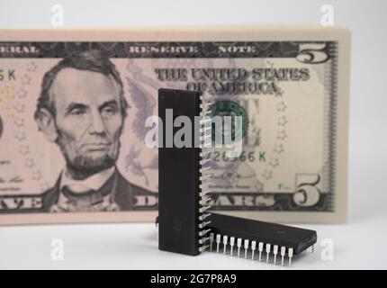De grandes puces informatiques placées à côté de 5 billets de banque en dollars américains. Concept d'investissement dans l'industrie des semi-conducteurs et la pénurie de puces d'or. Banque D'Images