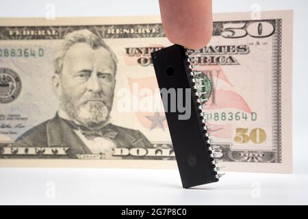 Grande puce d'ordinateur placée à côté de billet de 50 dollars US. Concept d'investissement dans l'industrie des semi-conducteurs et la pénurie de puces d'or. Banque D'Images