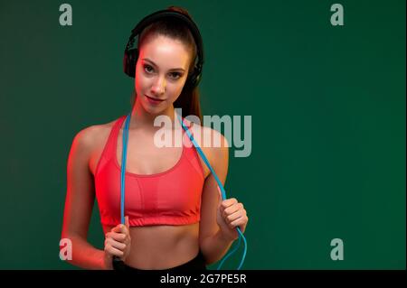 Femme sportive attrayante avec corde à sauter et femme forte d'écouter de la musique dans les écouteurs à l'intérieur Banque D'Images