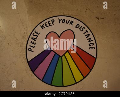 Panneau : « Veuillez garder votre distance », avec arc-en-ciel et cœur. Banque D'Images