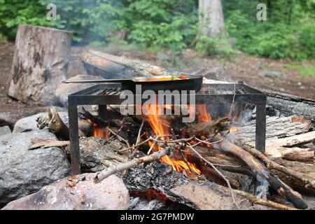 Faites la poêle avec de la nourriture frite sur le feu de camp dans la forêt Banque D'Images