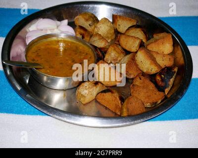 Repas traditionnel indien à base de poudre de farine de pois chiches présentée dans une assiette à dîner en métal argenté. Banque D'Images