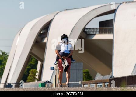 Un homme porte son fils devant le stade d'athlétisme conçu par Masachika Murata dans le parc olympique de Komazawa, Tokyo, le 10 juin 2021. Le parc a été construit pour les Jeux Olympiques de 1064 et reste un lieu de loisirs populaire. Robert Gilhooly photo Banque D'Images