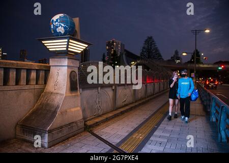 Les piétons passent par le pont olympique près du parc Yoyogi, Tokyo, le 21 juin 2021. Le pont a été construit dans le cadre d'un réseau routier améliorant l'accès aux principaux sites des Jeux Olympiques de 1964, Bien que n'aurait pas attiré l'attention au moment des Jeux de 1964, alors que les globes au sommet des quatre piliers et les reliefs de pierre représentant les Jeux Olympiques n'ont été ajoutés que plus de 25 ans plus tard. Robert Gilhooly photo Banque D'Images