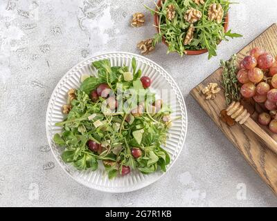 La combinaison de saveurs de raisins rôtis caramélisés avec du miel, des arugules, des noix et du fromage pecorino. Salade végétarienne savoureuse pour le déjeuner ou accompagnement pour le déjeuner Banque D'Images