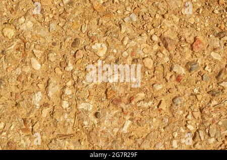 La texture d'une route de terre avec de petites pierres et du sable. Banque D'Images