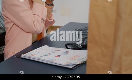 Directeur exécutif ayant un repas à emporter commander manger un délicieux sandwich pendant le déjeuner dans le bureau de démarrage. Femme d'affaires buvant du café analysant les statistiques ayant pause déjeuner Banque D'Images