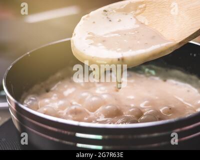 Sauce carbonara aux champignons maison dans une casserole sur la cuisinière électrique dans la cuisine. Concepts sains de cuisine italienne. Banque D'Images