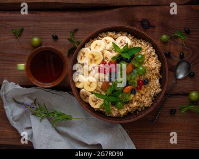 Bol de porridge à flocons d'avoine avec baies fraîches, fruits, noix, feuilles de menthe tasse à thé. Nourriture saine repas d'avoine matin petit déjeuner vue de dessus. Grain entier c Banque D'Images