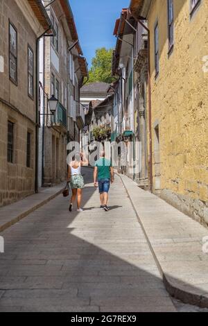 Guimarães / Portugal - 12 09 2020 : vue sur une rue ancienne et étroite avec des bâtiments classiques dans le centre ville de Guimarães, couple marchant sur fond Banque D'Images