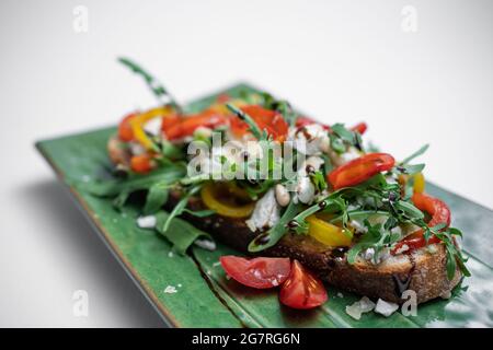 bruschetta ou pain grillé à l'arugula, aux tomates et au fromage sur fond blanc Banque D'Images