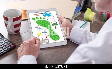 Concept d'empreinte carbone présenté sur une tablette tenue par un homme Banque D'Images