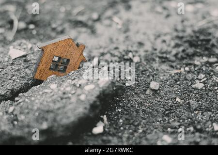 Destruction de bâtiments résidentiels et concept de tremblement de terre . Maison de jouets en bois tombée dans une fissure dans la terre. Banque D'Images