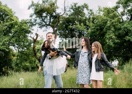 Parents souriants avec deux filles jouant et s'amusant pendant les week-ends à l'air frais. Une jeune famille de quatre personnes qui apprécie de passer du temps ensemble dans la nature. Concept d'été. Banque D'Images